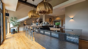 A modern kitchen with a central island, bar stools, hanging light fixtures, and a large window providing natural light.