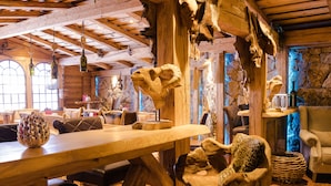 A rustic interior with wooden beams, a stone wall, and various animal skulls displayed as decor.