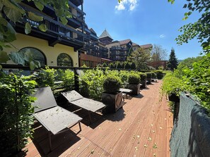 Eine Außenpatio mit Liegestühlen, Topfpflanzen und Blick auf ein Gebäude mit Balkonen.
