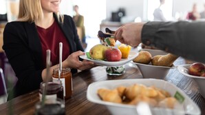 A dining table with a plate of food, a glass of drink, and a jar of jam.