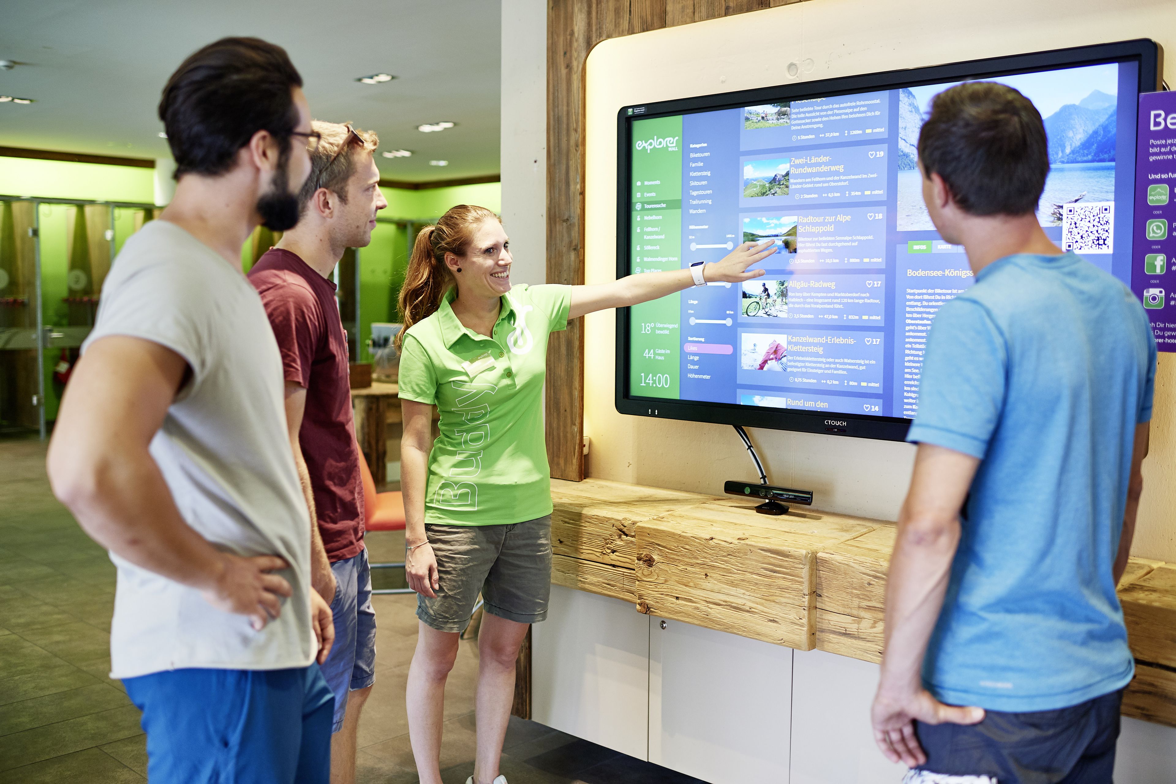 A group of people interacting with a digital display in a modern setting.