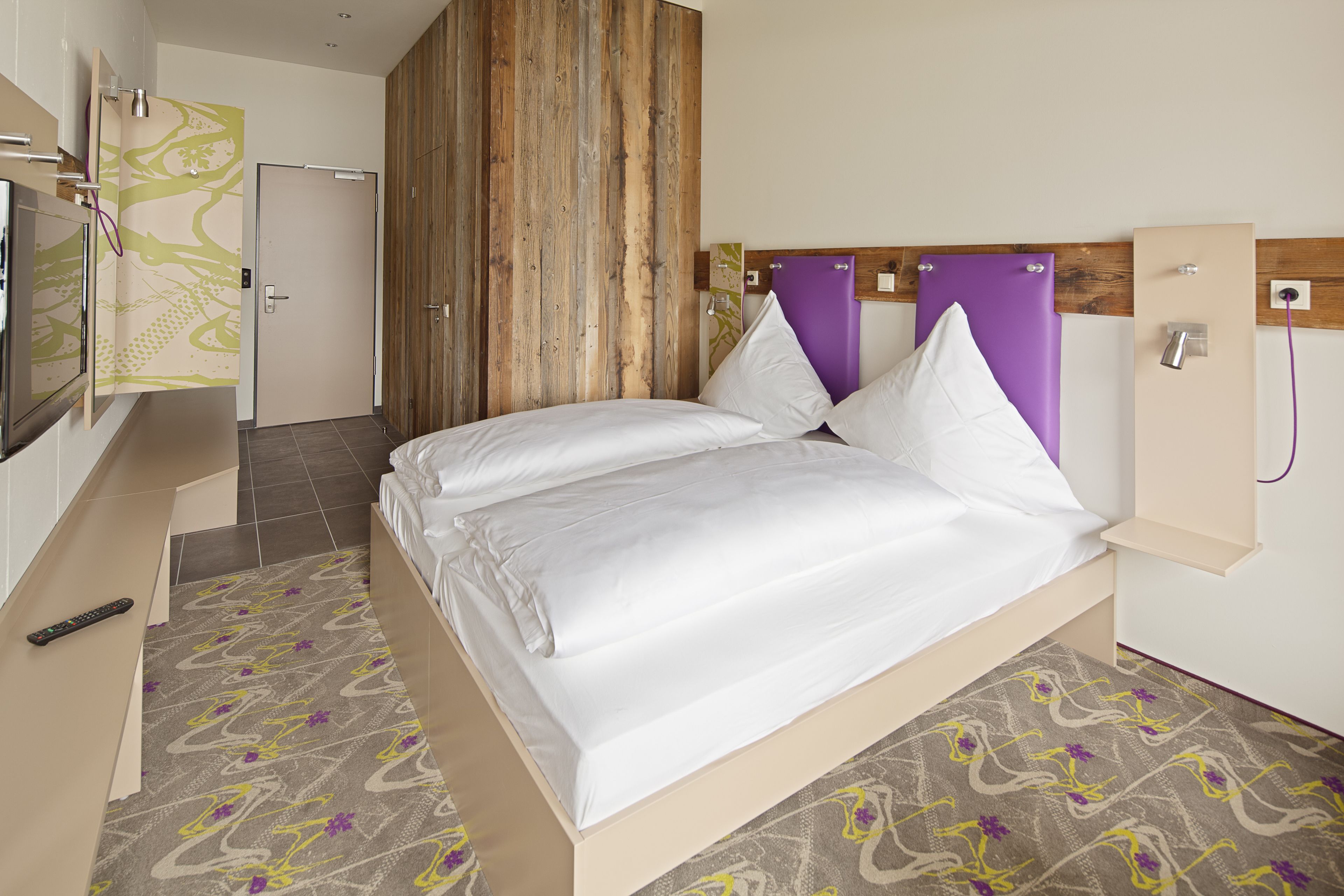 Una habitación de hotel moderna con cama, televisión y zona de ducha.