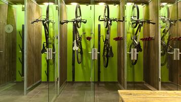 Een badkamer met groene wanden, houten kasten en fietsen aan de muur bevestigd.
