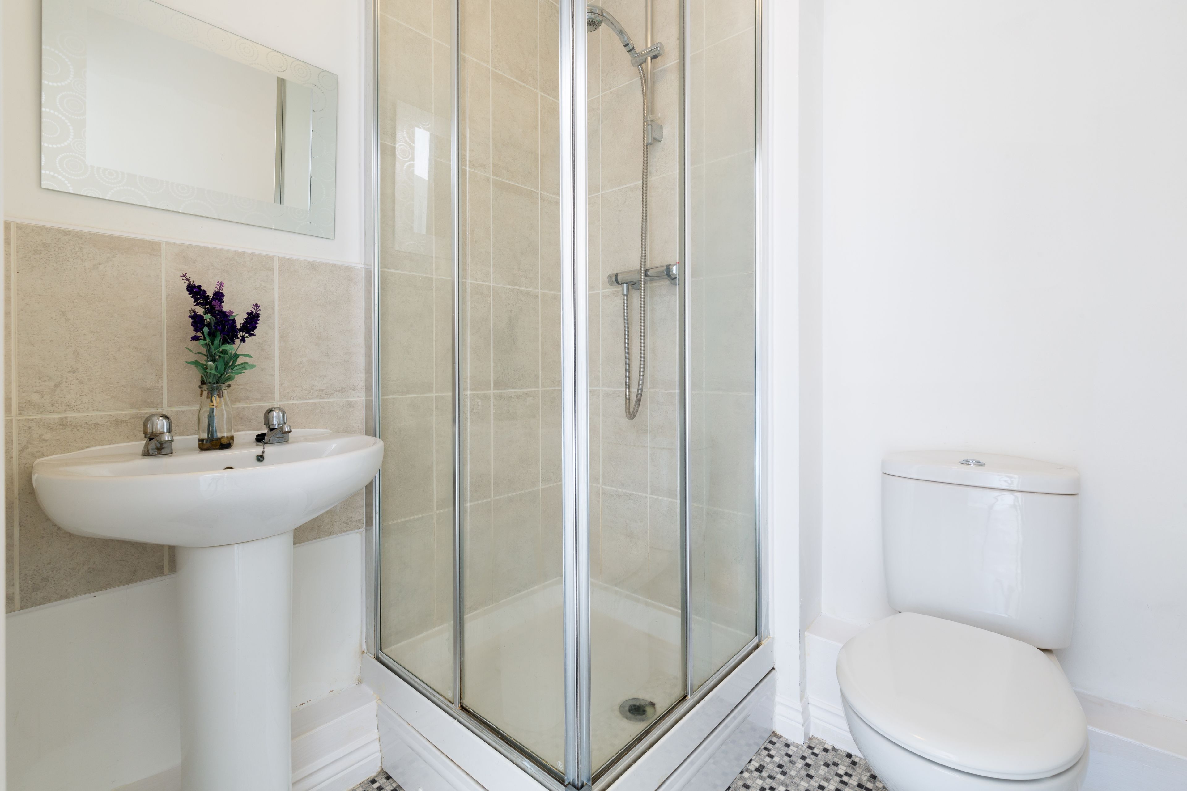 A bathroom with a glass-enclosed shower, a white sink, and a toilet.