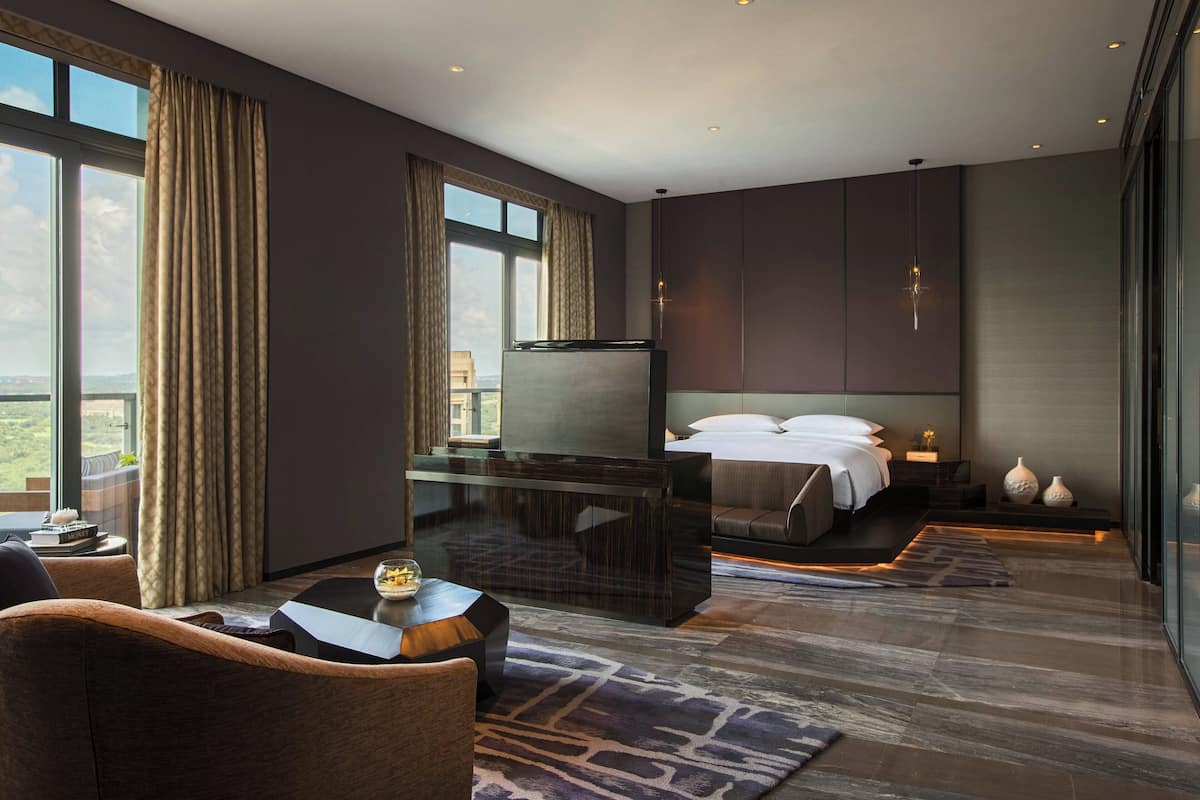 Habitación de hotel moderna con una cama grande, un escritorio, una silla y vistas a la ciudad.