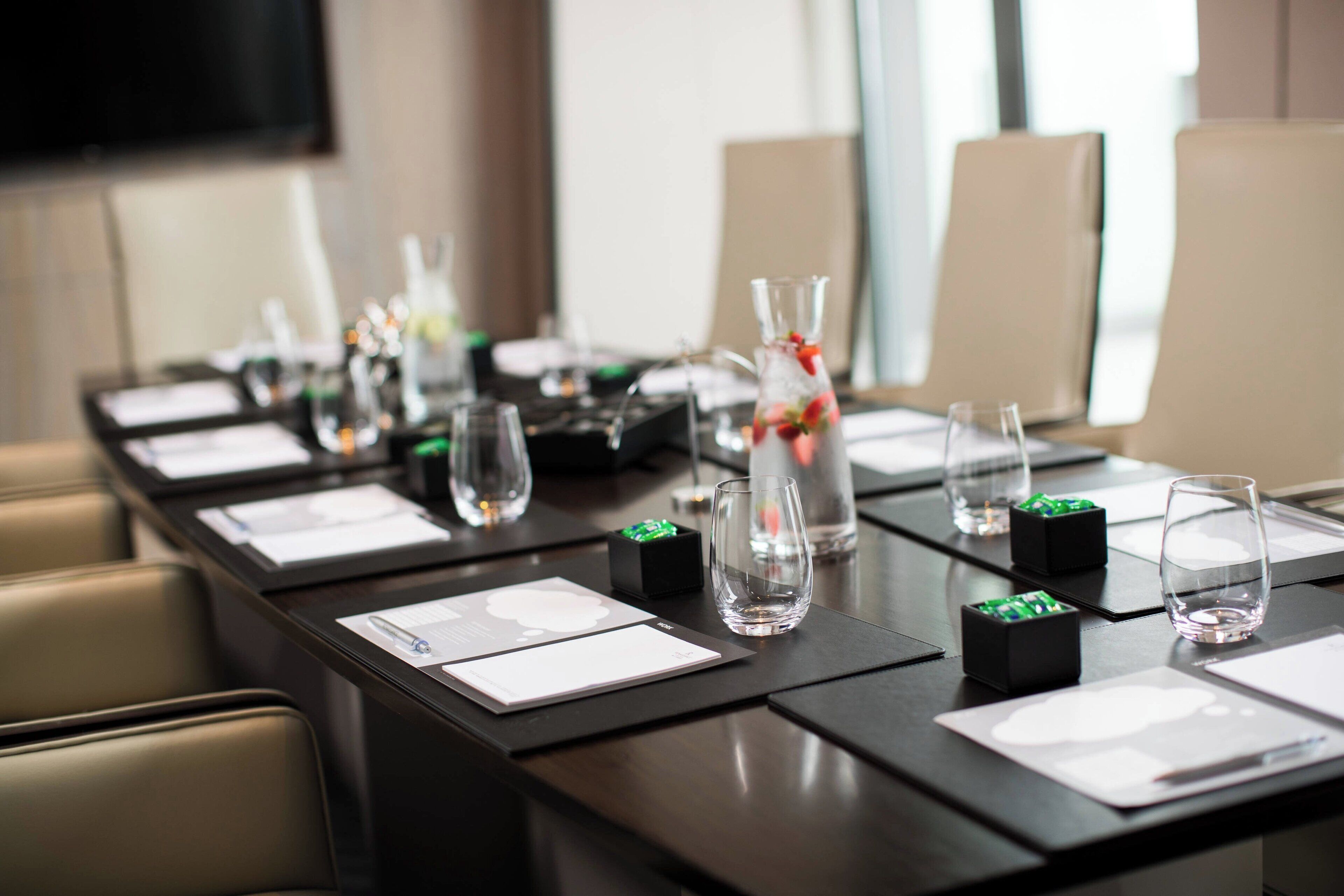 Une table de conférence dressée avec des documents, des verres et des objets décoratifs.