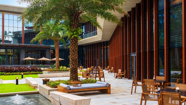 Un espace extérieur aménagé avec des tables et des chaises, un palmier et un élément décoratif aquatique.