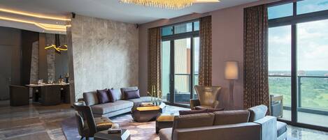 A spacious living room with a modern chandelier, a large sofa set, and a dining area with a table and chairs.