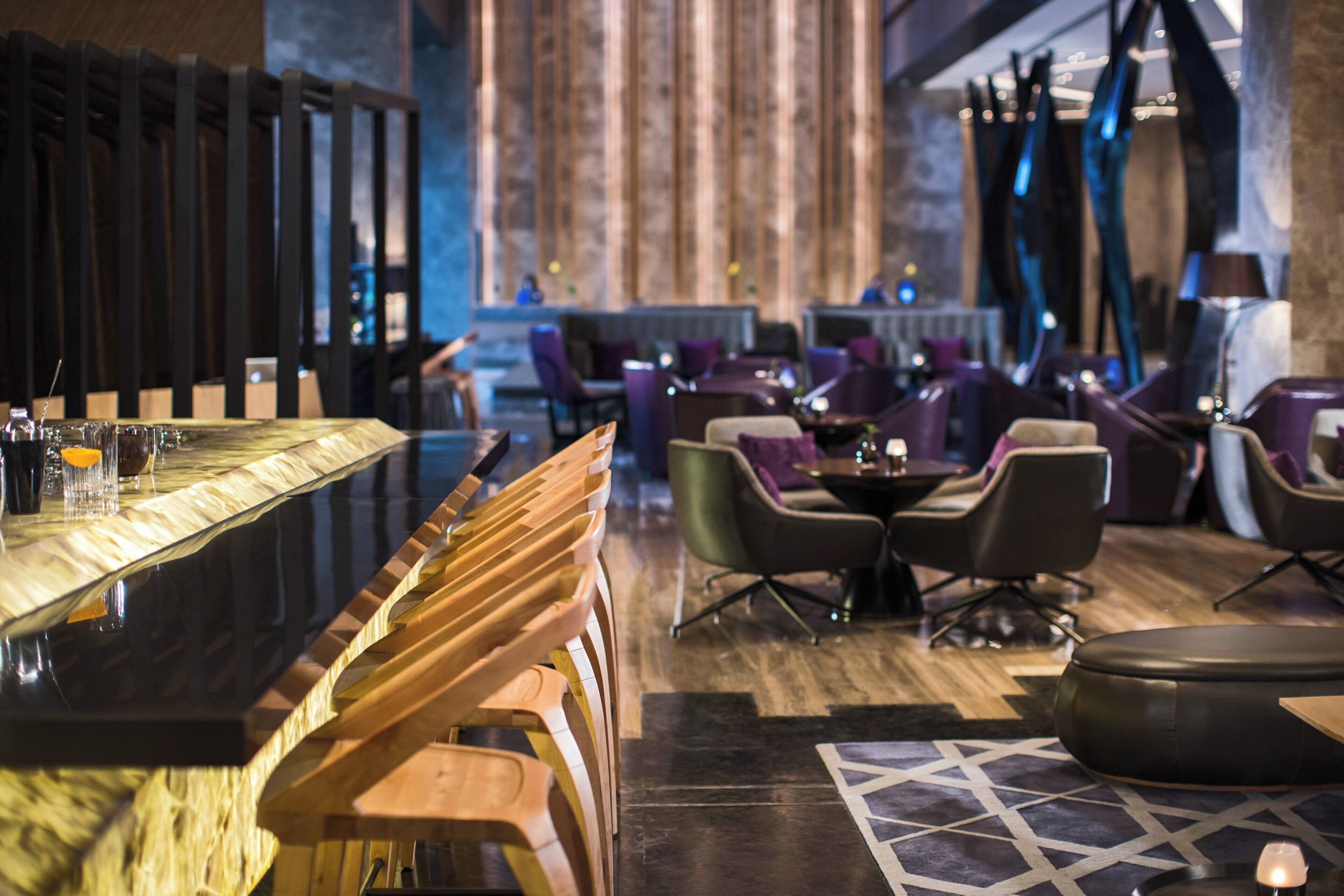 Un área de bar con taburetes de madera, una barra y un espacio de estar con sillas y una mesa.