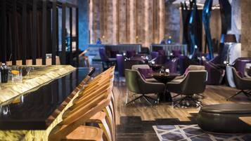 Un área de bar con taburetes de madera, una barra y un espacio de estar con sillas y una mesa.