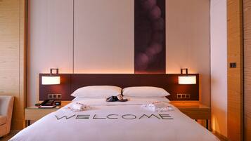 Una habitación de hotel con una cama, dos lámparas de noche, una mesita de noche con un teléfono y una pared con un panel decorativo grande.