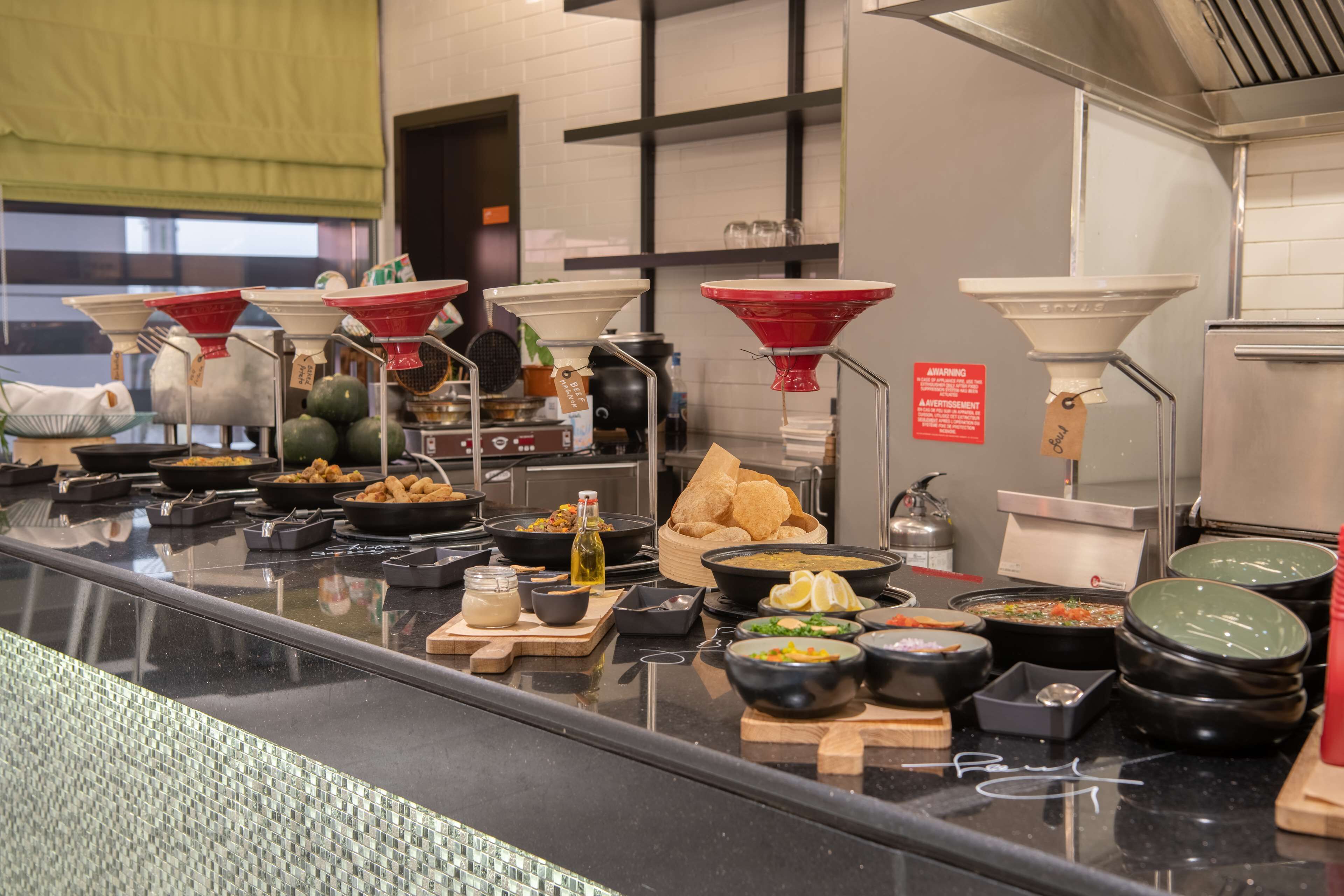 A buffet counter with various dishes and condiments.