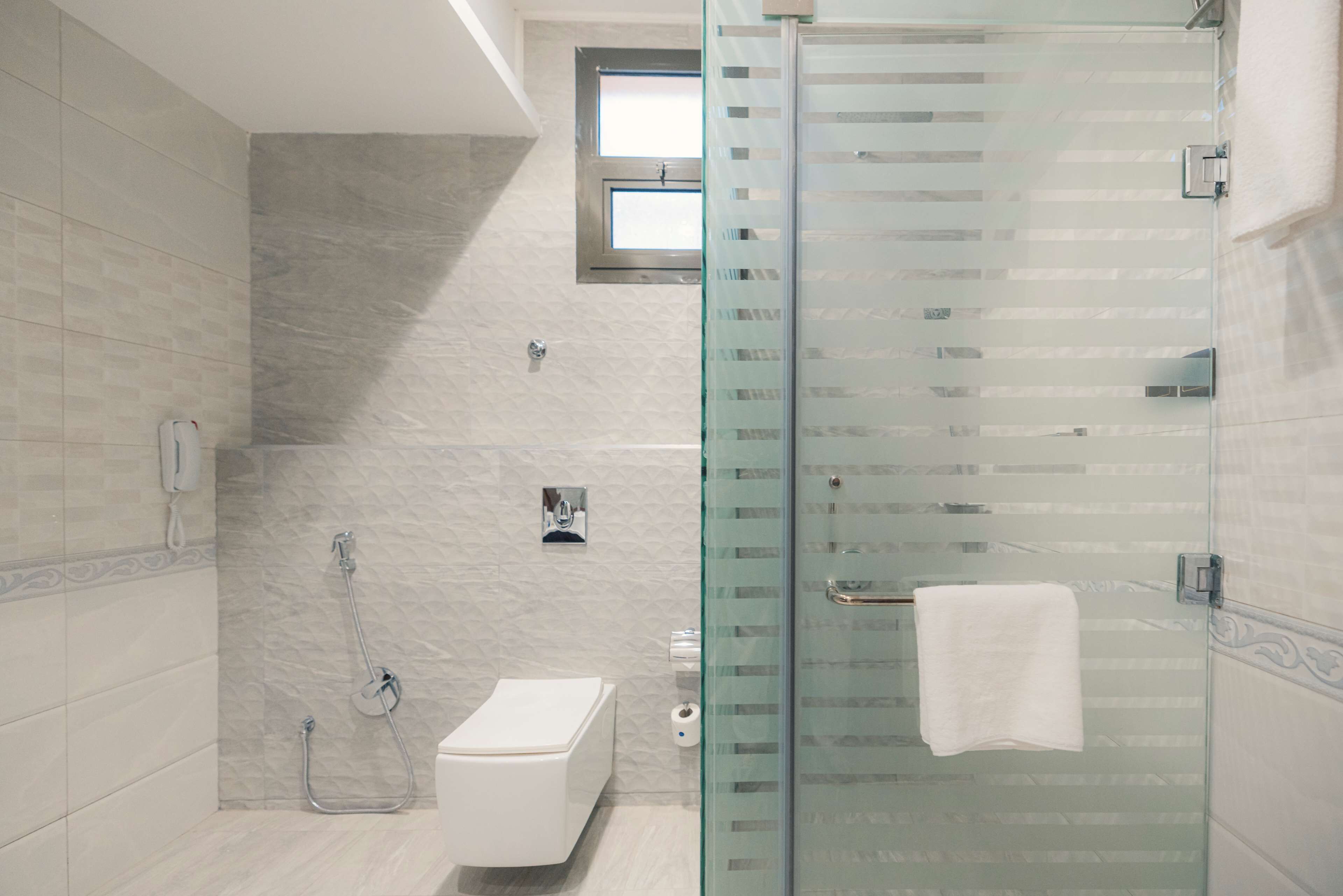 Une salle de bain moderne avec une douche à parois de verre, des toilettes et un porte-serviettes.