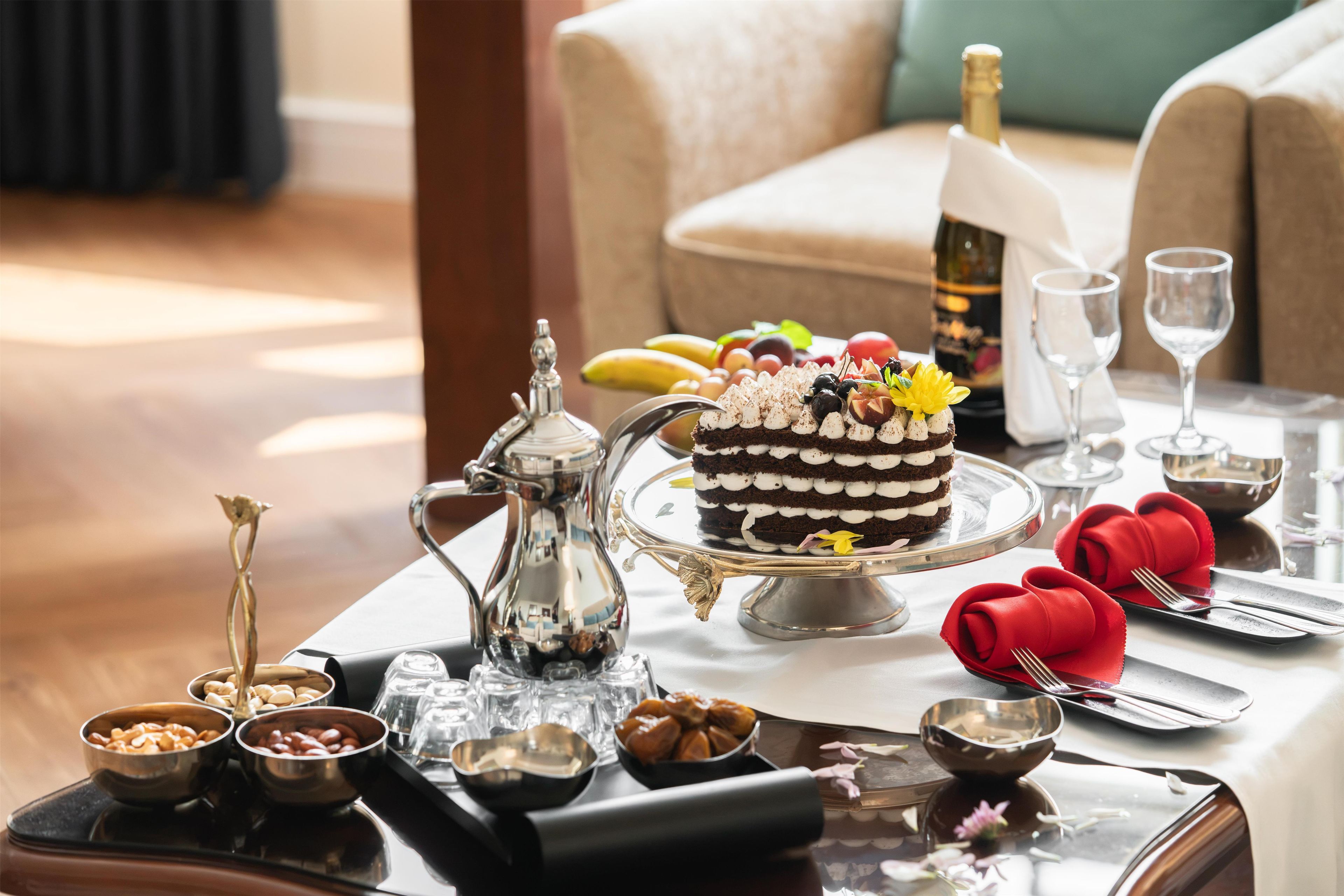 A dining table set with a cake, wine, and various dishes.