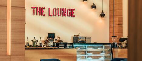 Un moderno salón con un mostrador de recepción de madera, una vitrina de vidrio y un letrero de neón que dice "THE LOUNGE".