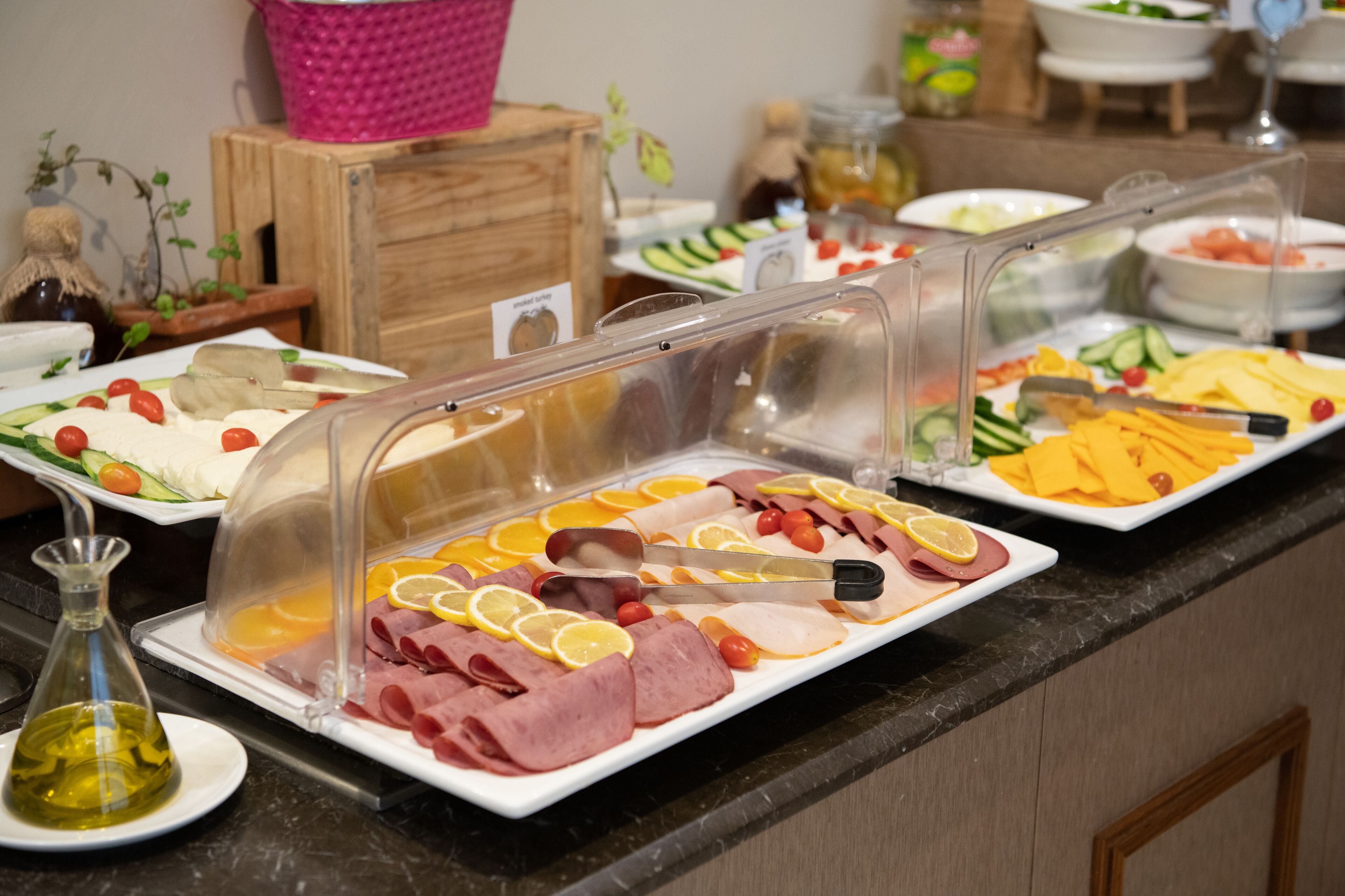 A buffet with various food items including meats, cheeses, and fruits.