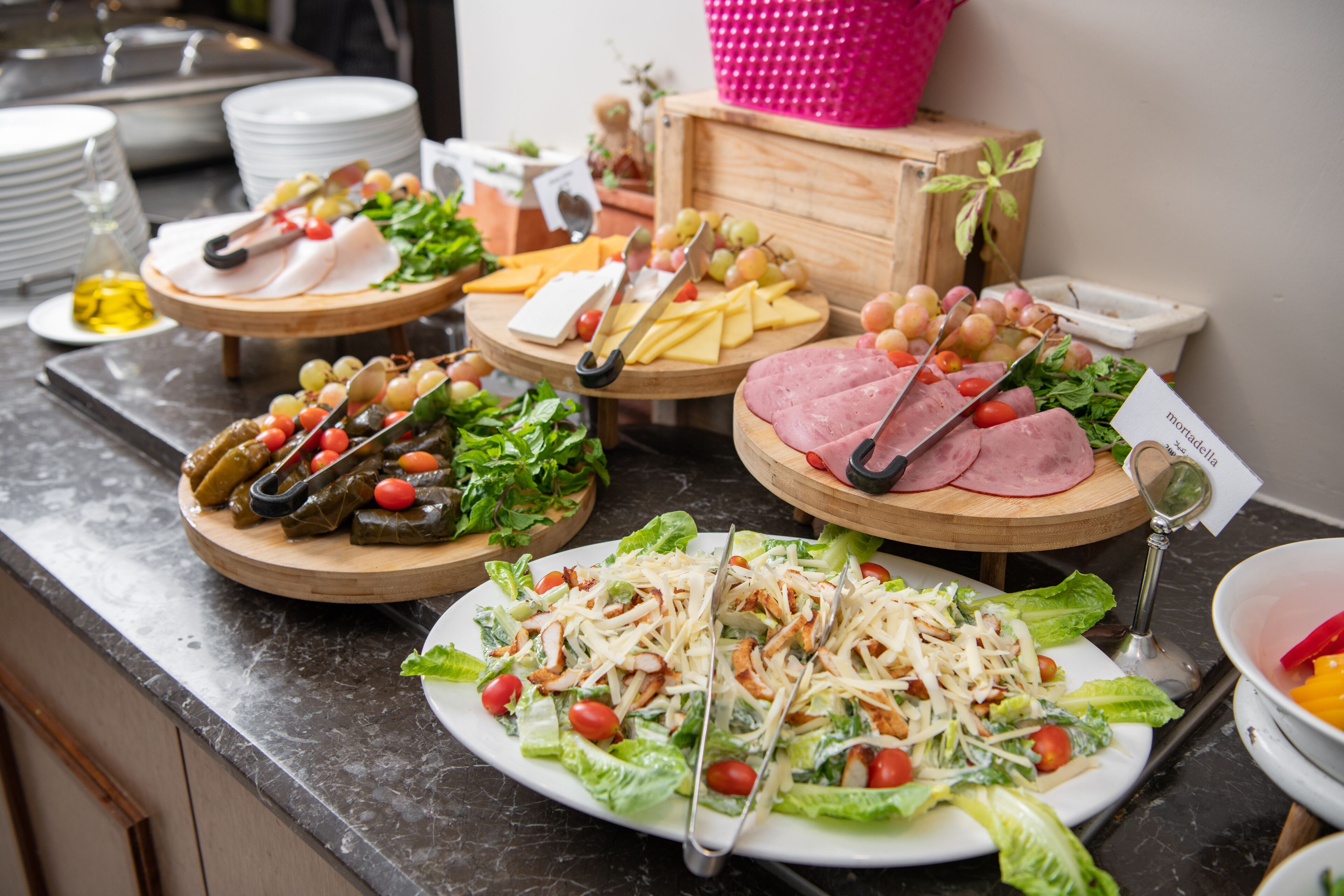 A buffet with various dishes including salads, meats, and cheeses.