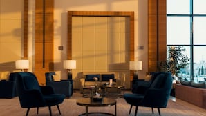 A spacious lobby with a large seating area, a central coffee table, and a large window offering a view of the city. - Radisson Blu Hotel, Buraidah (Buraydah)