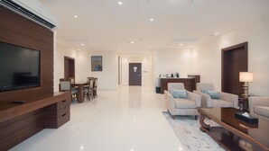 A modern living room with a flat-screen TV, a dining area, and a sofa set. - Radisson Blu Hotel, Buraidah (Buraydah)