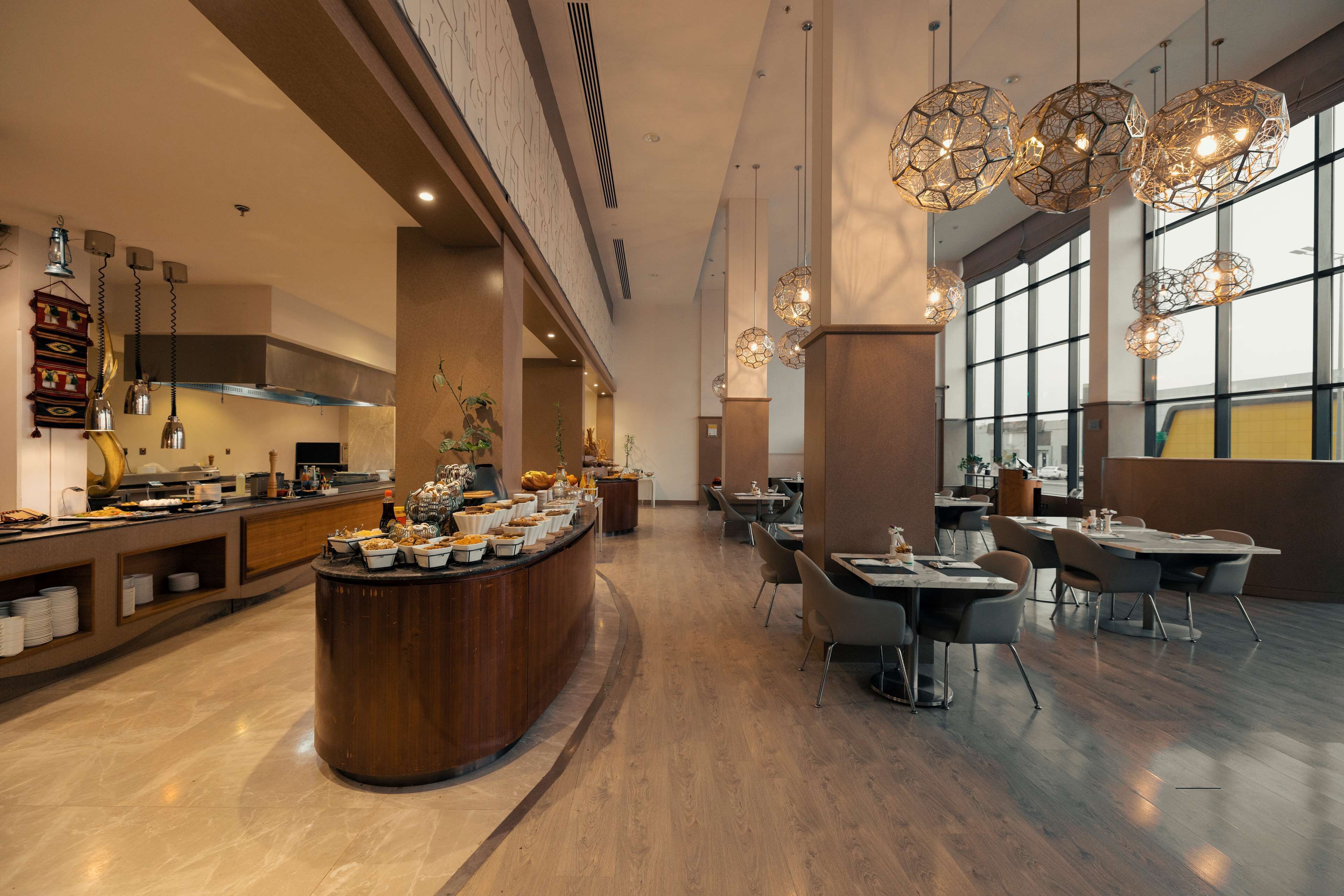 A modern dining area with a central buffet, high ceilings, and large windows.