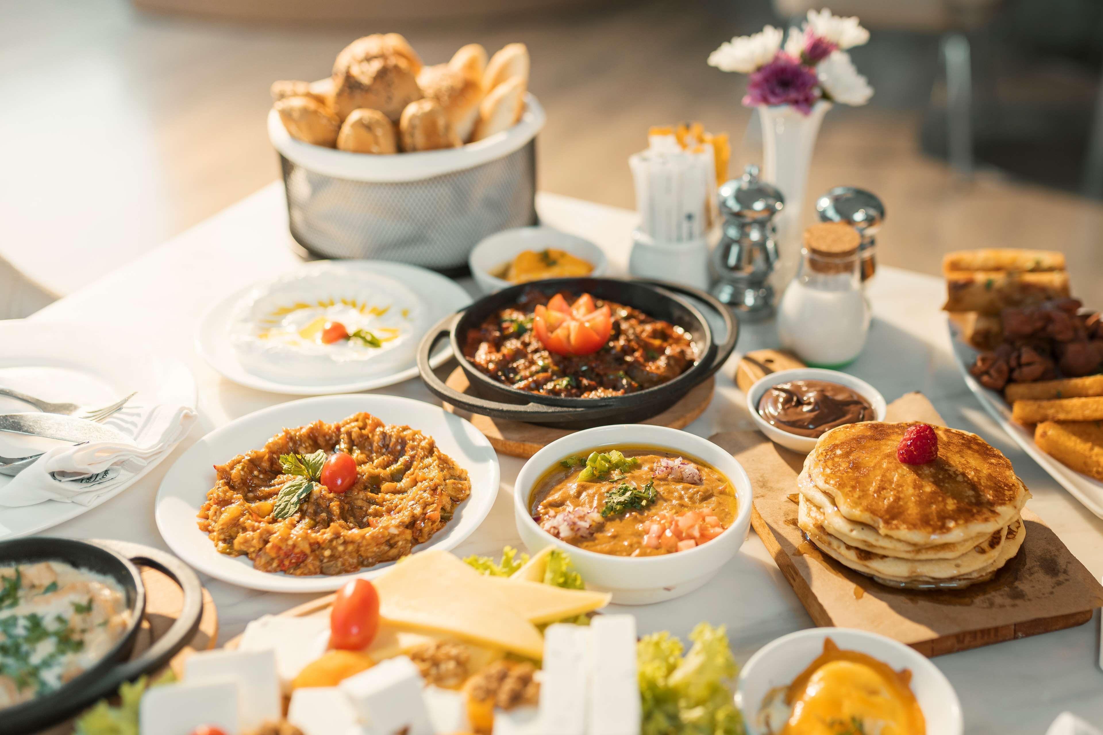 Een tafel met verschillende gerechten, waaronder pannenkoeken, een kom soep en een bord nachos.