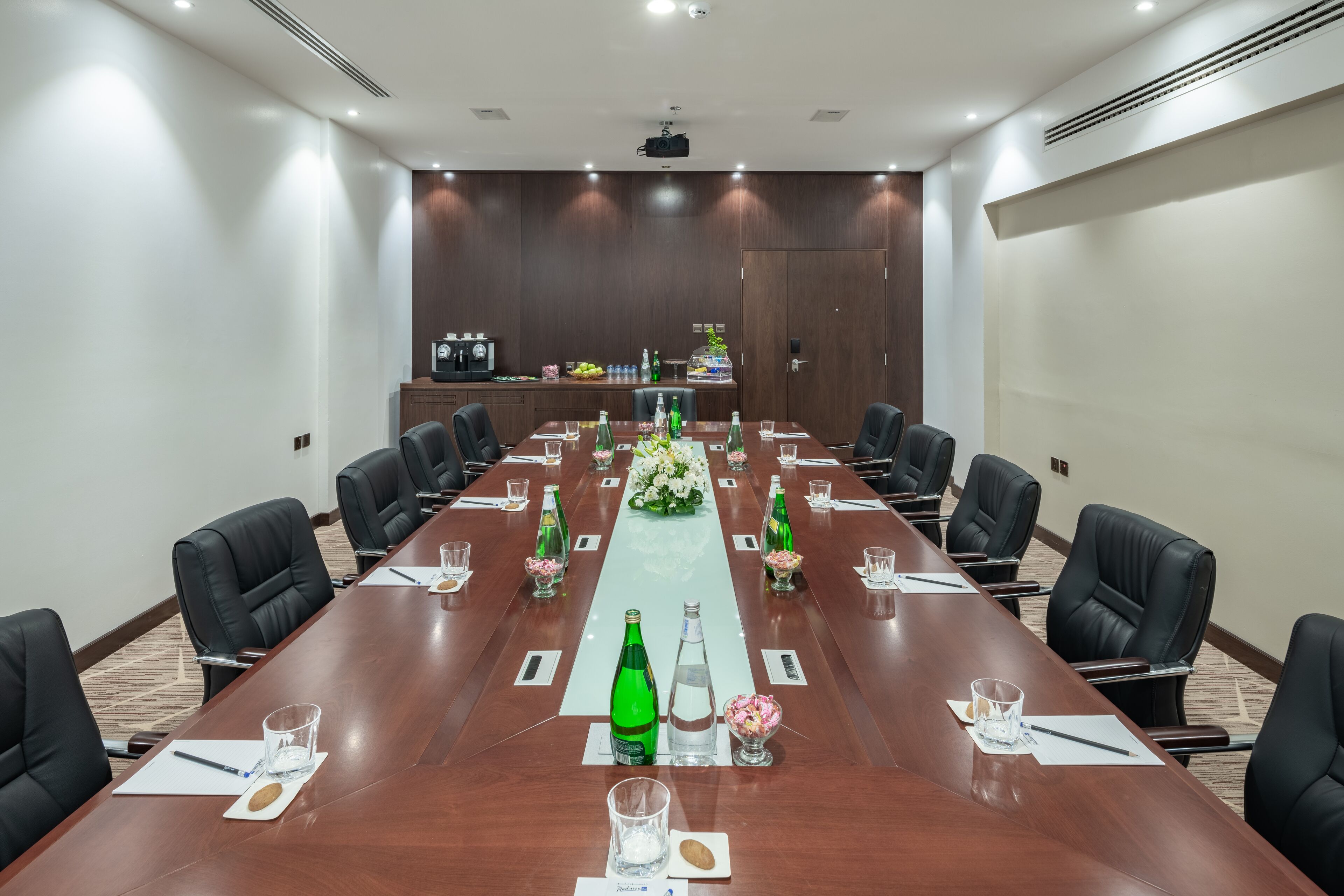 A conference room with a long table, black chairs, and a whiteboard.