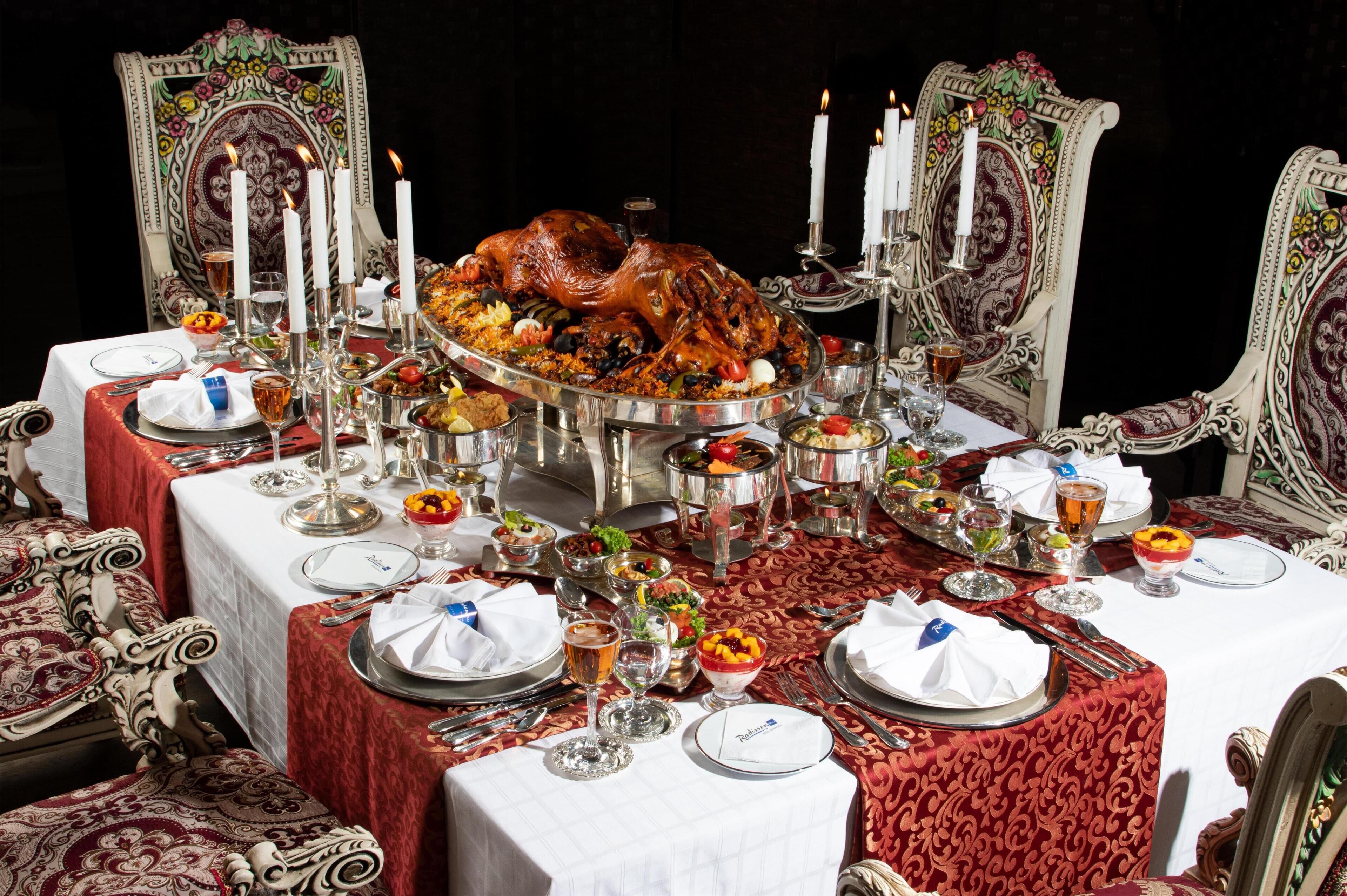 A formal dining table set with a roasted turkey centerpiece, surrounded by various dishes and glasses.