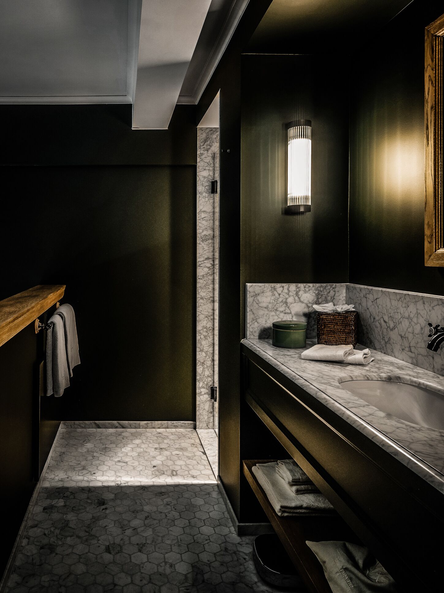 A modern bathroom with a dark color scheme, a marble sink, and a towel rack.
