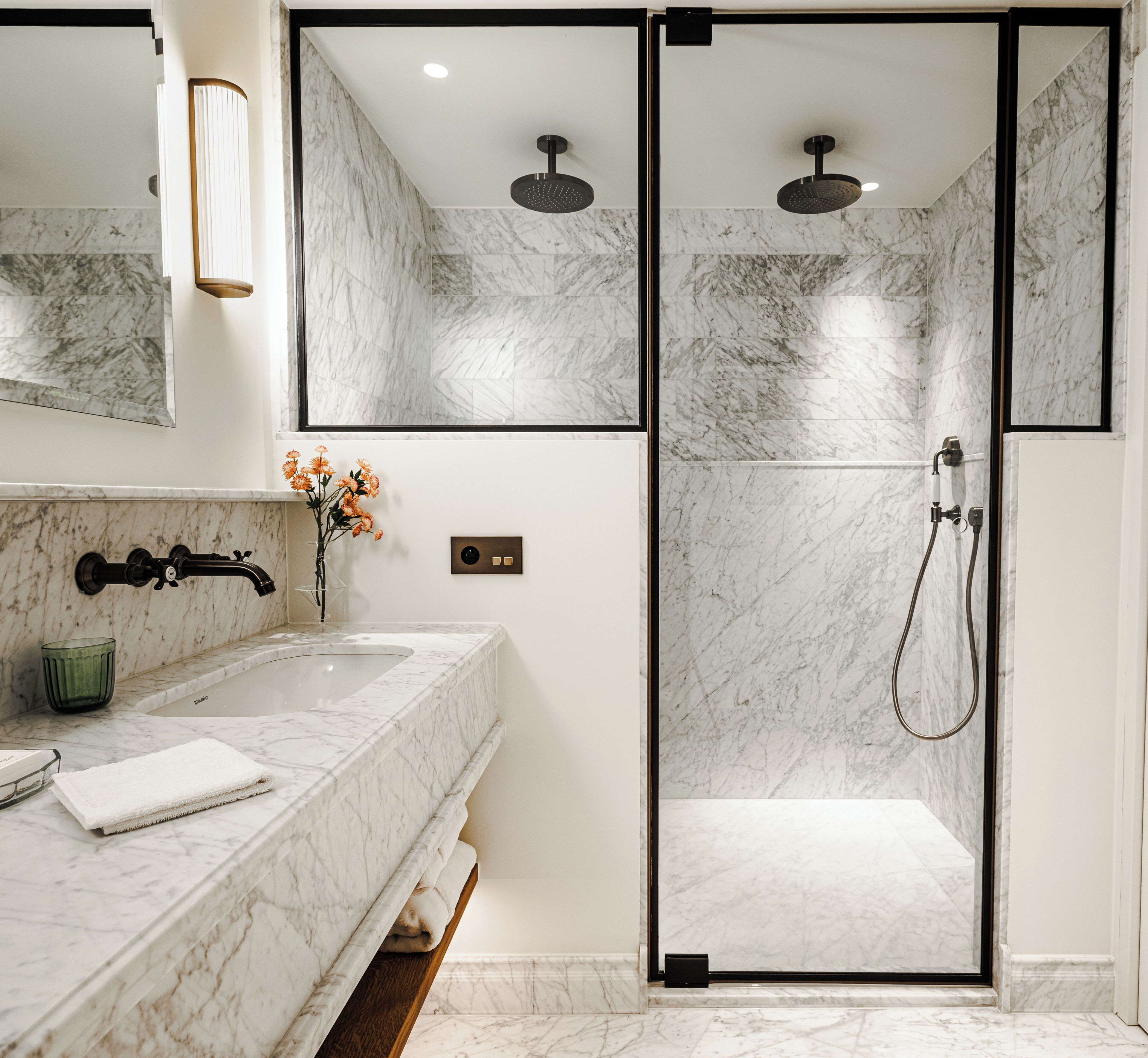 A modern bathroom with a marble sink, a glass shower enclosure, and a mirror above the sink.