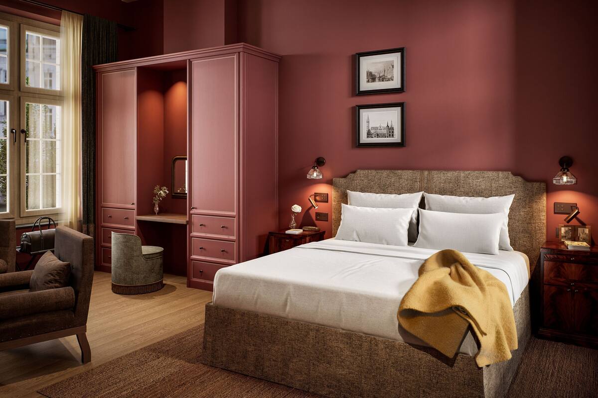 A bedroom with a large bed, a wardrobe, a chair, and two bedside tables with lamps.