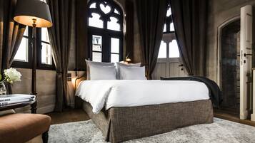Een slaapkamer met een groot bed, een nachtkastje met een lamp en een stoel.