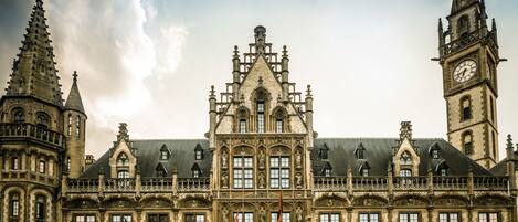 A historic building with intricate architectural details, including a prominent clock tower and a central tower with a spire.