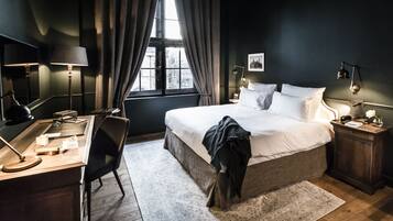 Ein Schlafzimmer mit Bett, Schreibtisch, Stuhl und einem Fenster mit Vorhängen.