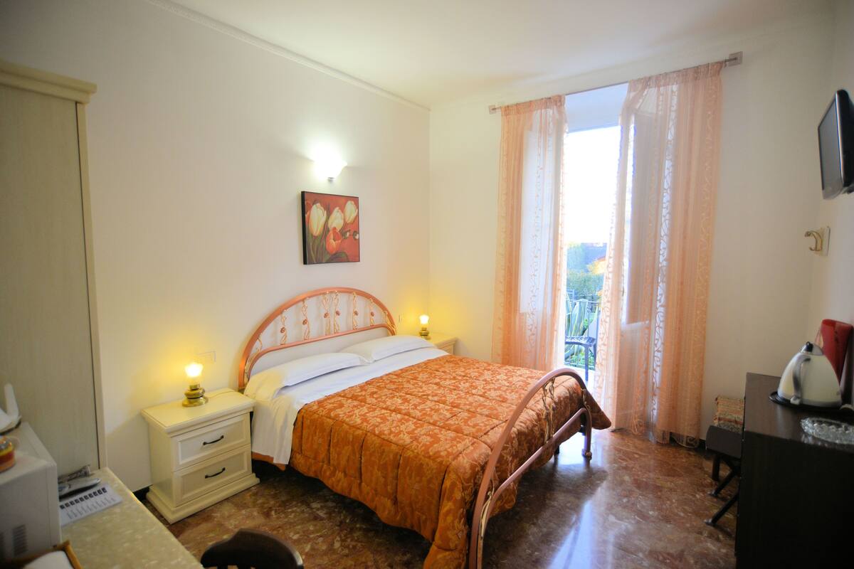 A bedroom with a bed, bedside tables, a desk, and a window with curtains.