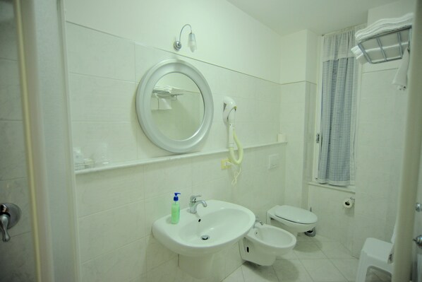 A bathroom with a sink, bidet, toilet, and a mirror.