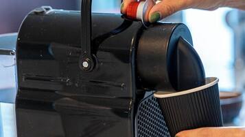 A person using a coffee machine with a black handle and a cup holder.