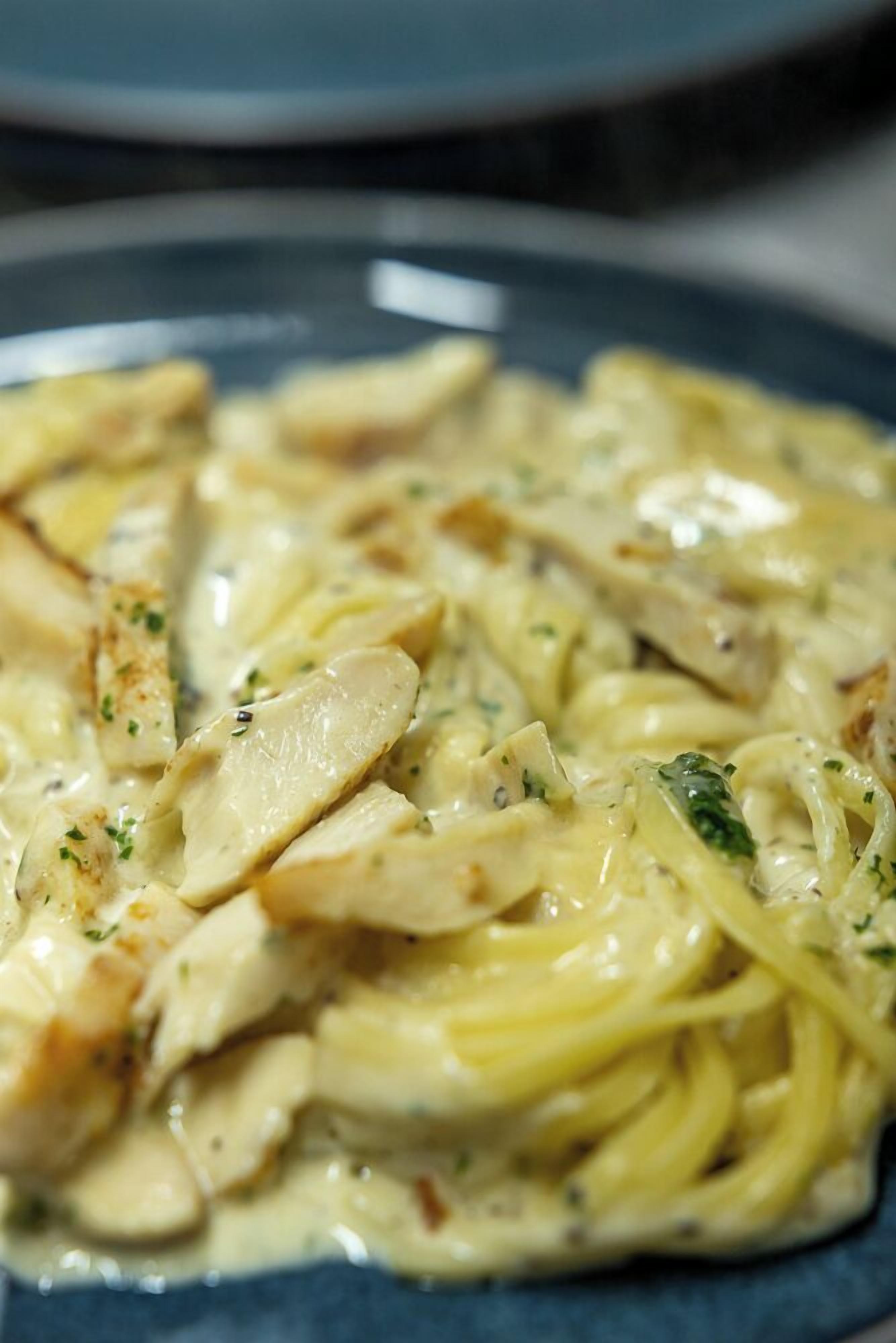 En tallrik med krämig pasta, kyckling och örter.