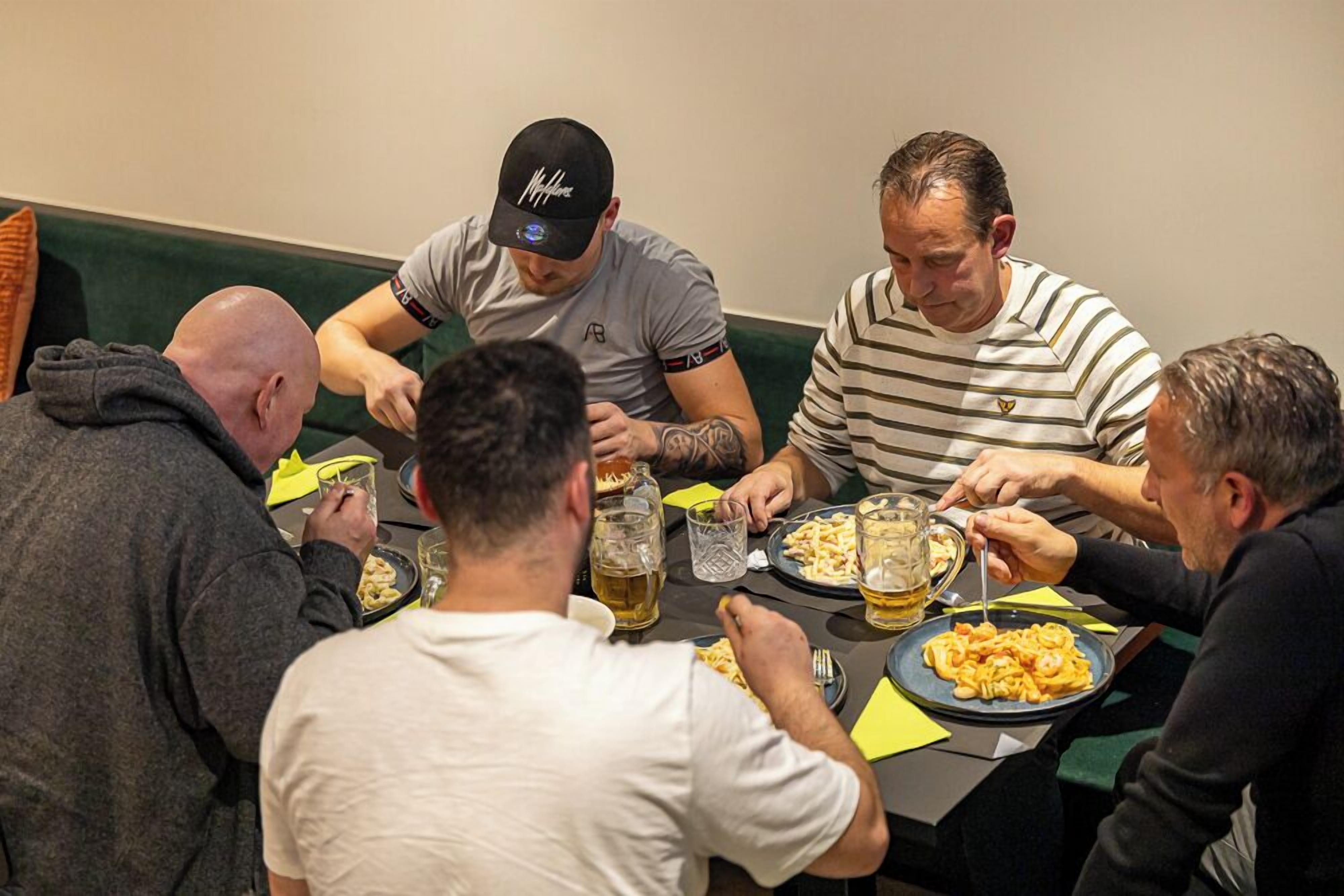 Un grupo de personas cenando en una mesa, con platos de comida y bebidas.