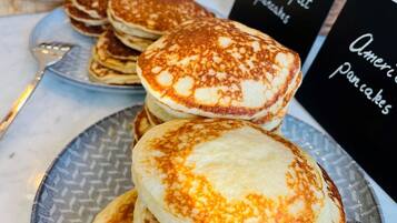 A stack of pancakes on a plate with a sign indicating 'American Pancakes'.