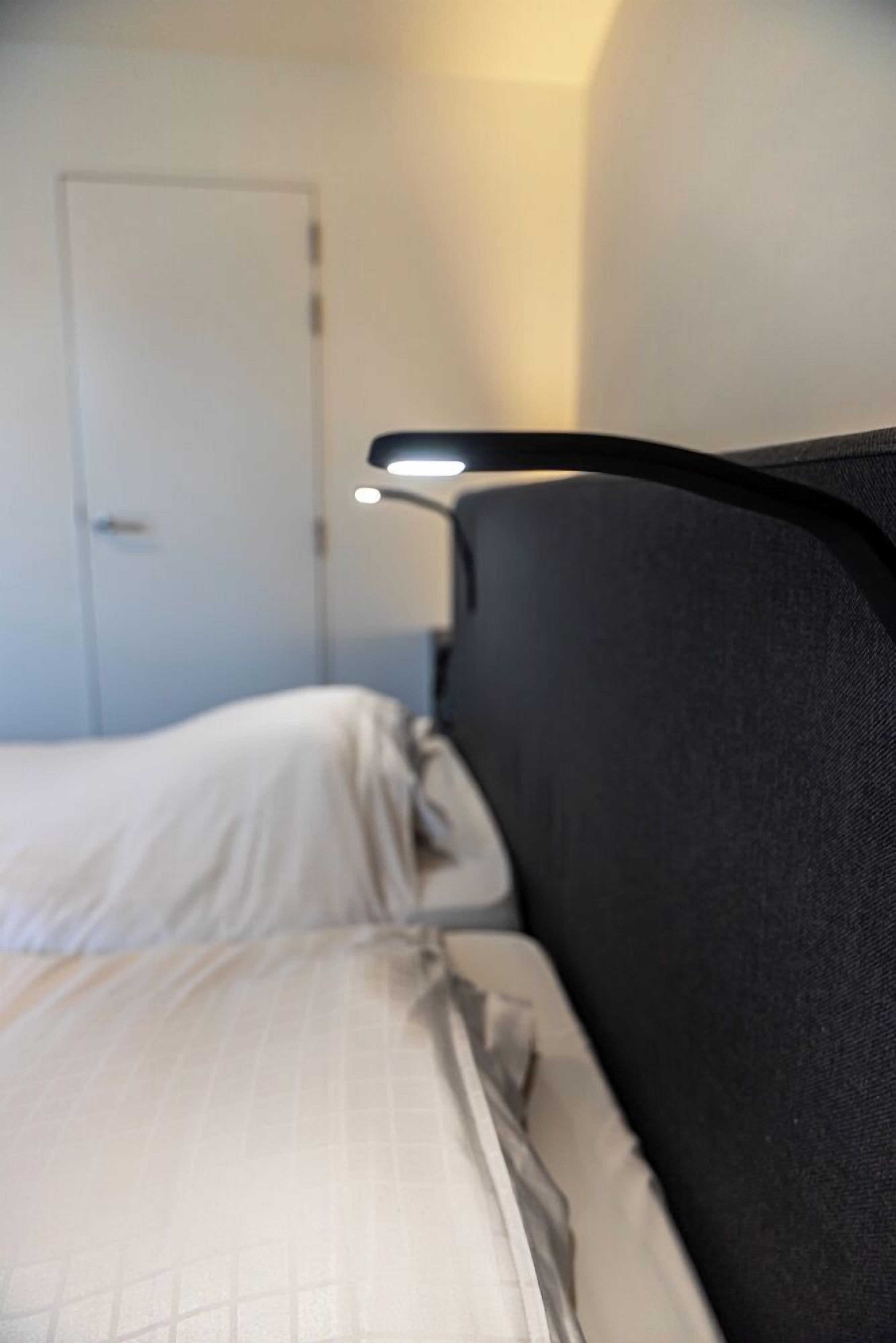 A bed with a headboard and a bedside lamp.
