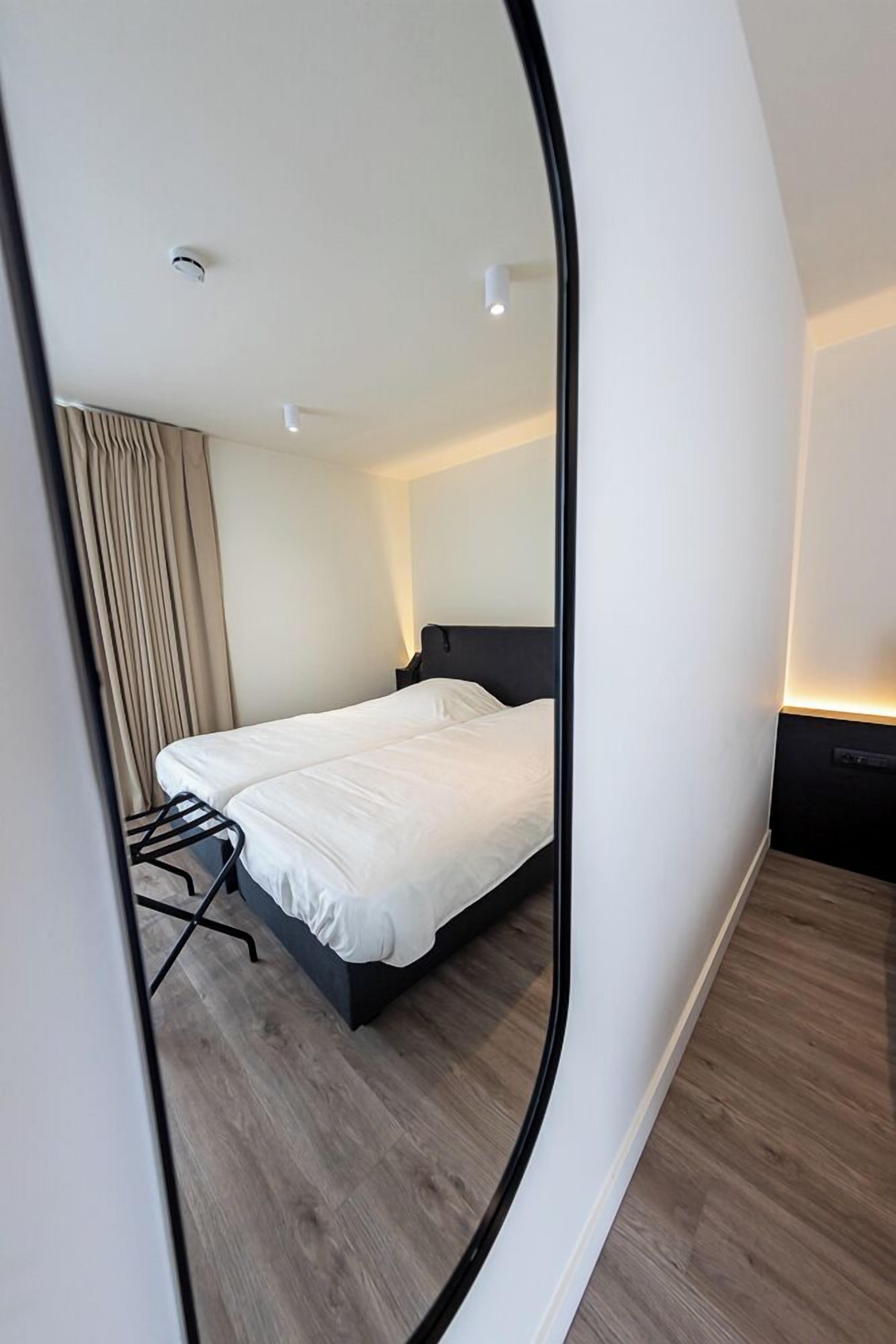 A modern hotel room with a bed, a desk, and a chair.