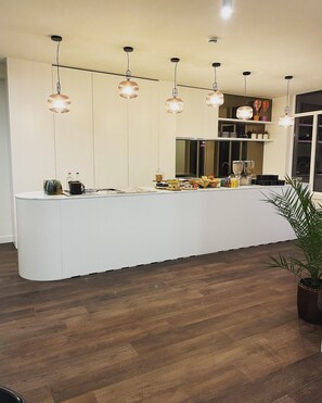 Une cuisine moderne dotée d’un îlot central, de luminaires suspendus et d’une grande fenêtre.