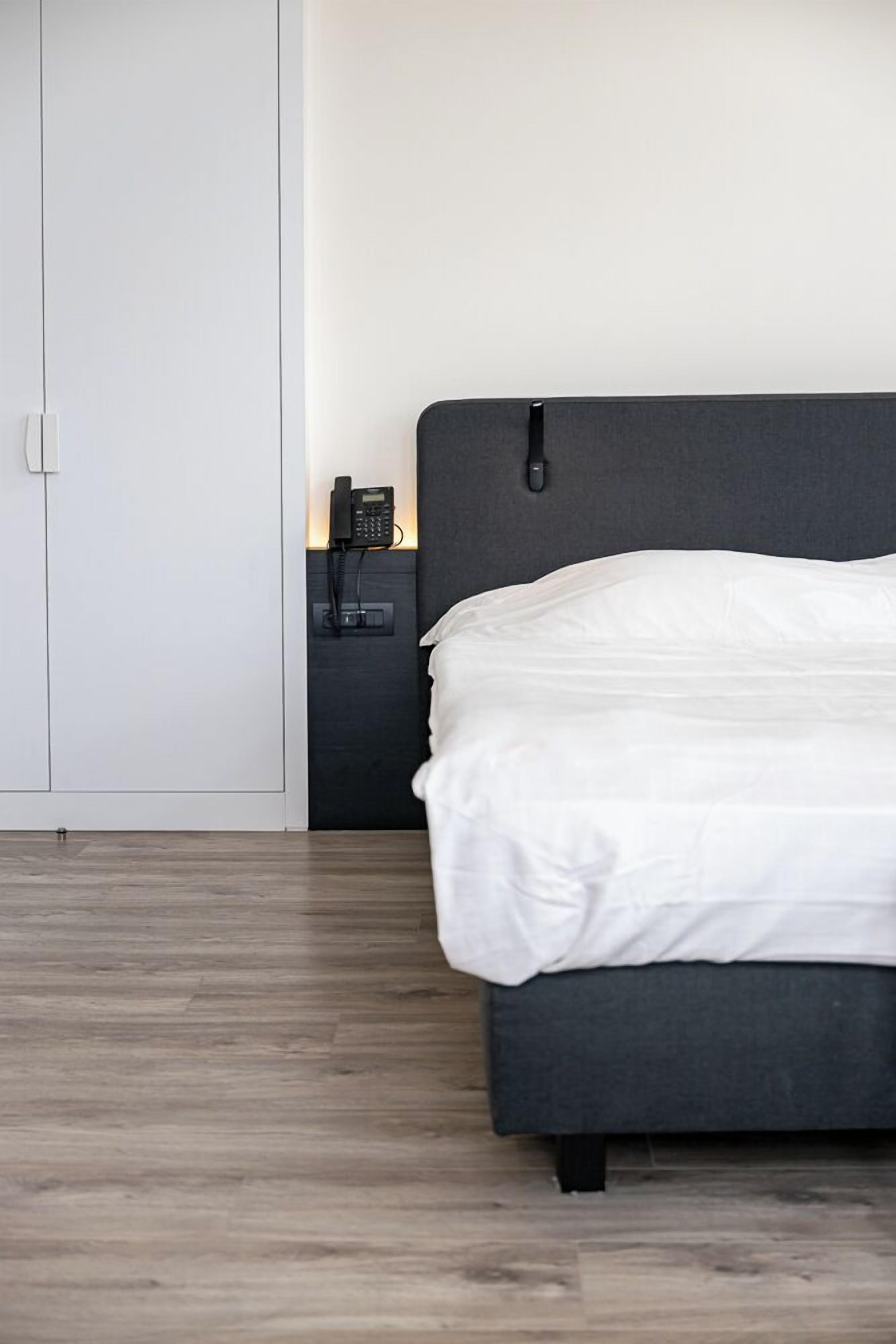 Une chambre à coucher avec un lit, une table de chevet, un téléphone et une armoire.