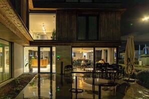 An outdoor dining area with tables and chairs, a wooden deck, and a glass enclosure leading to an indoor space. - Hotel Bell-X (Wevelgem)