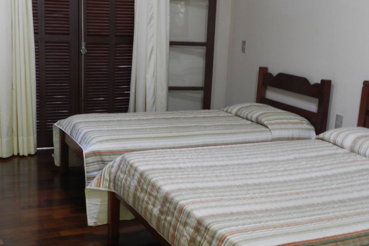 Een slaapkamer met twee eenpersoonsbedden, houten hoofdborden en een houten vloer.
