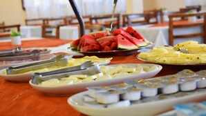Una mesa de buffet con diversos alimentos, incluyendo sandía, queso y sushi.