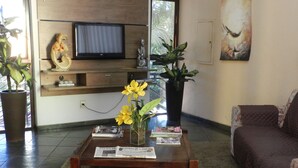 Una sala de estar con una mesa de centro de madera, un televisor montado en la pared, un sofá y varias plantas en macetas.