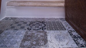 Una escalera con baldosas estampadas que lleva a una puerta con picaporte de latón.