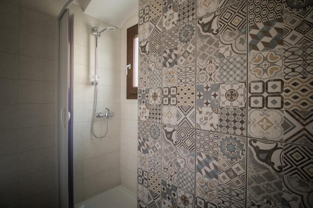 A shower area with a glass door, a showerhead, and a window.