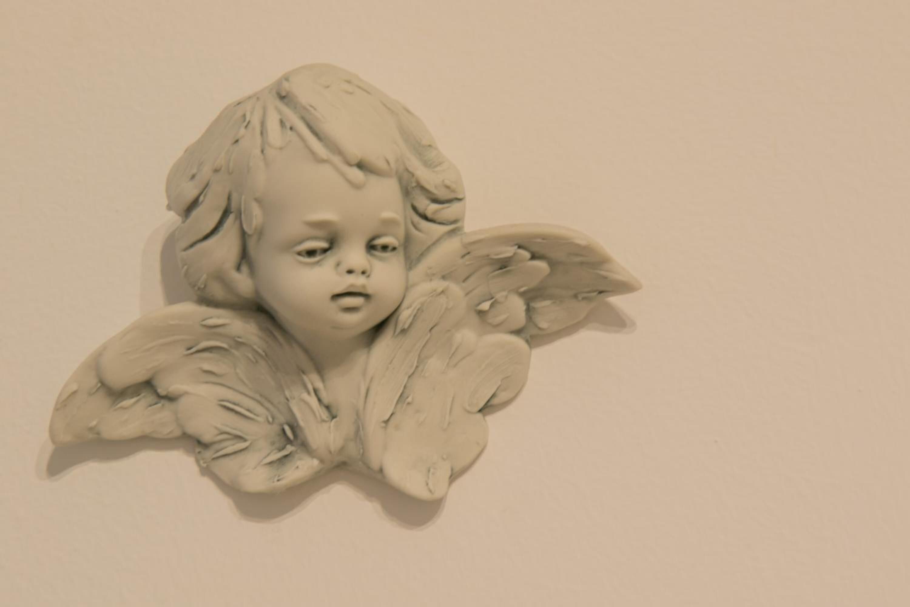 Escultura de um anjo com asas, fixada na parede.